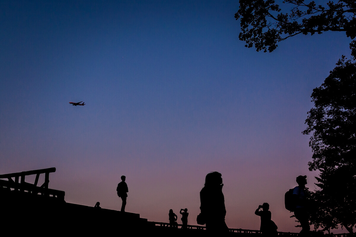 夕暮れ時に飛行機を撮る人々